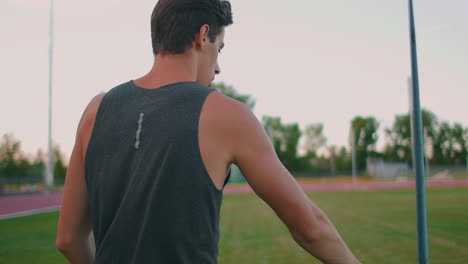 Ein-Speerwerfer-Läuft-Mit-Speeren-Durch-Das-Stadion-Und-Sammelt-Sie-Ein.-Gehen-Sie-Mit-Einem-Speer-In-Der-Hand-Vor-Dem-Hintergrund-Der-Stadiontribüne.-Das-Training-Des-Olympiasiegers.